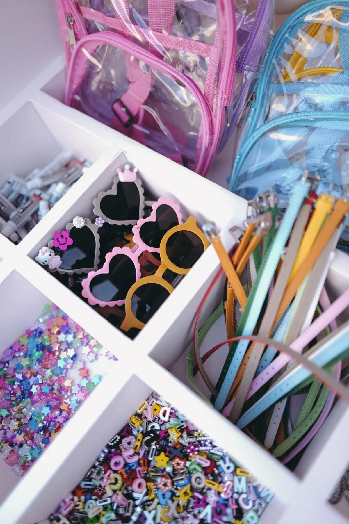 Trays of heart sunglasses, charms and colourful straps for crafting