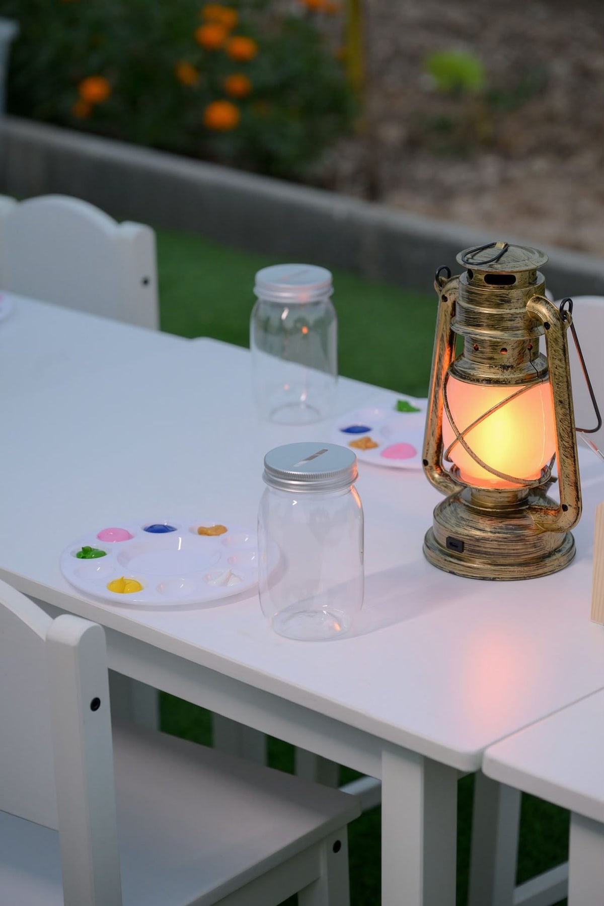 Jar painting stations set up at dusk with a glowing lantern