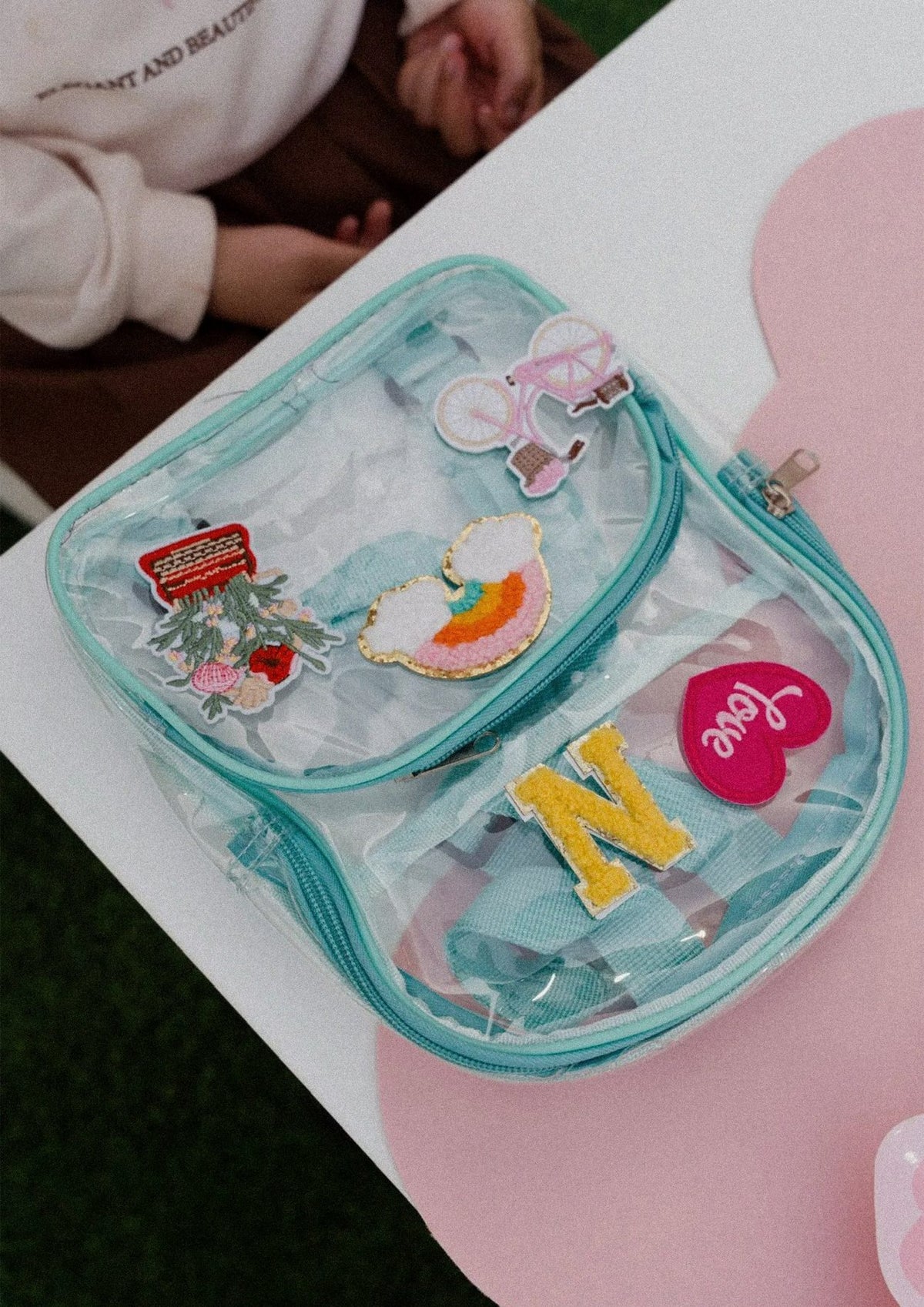A clear bag decorated with colourful patches